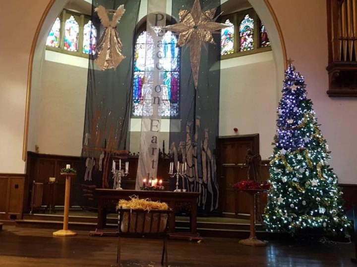 An image of the church at Christmas time, with a decorated altar, banners and a Christmas tree.