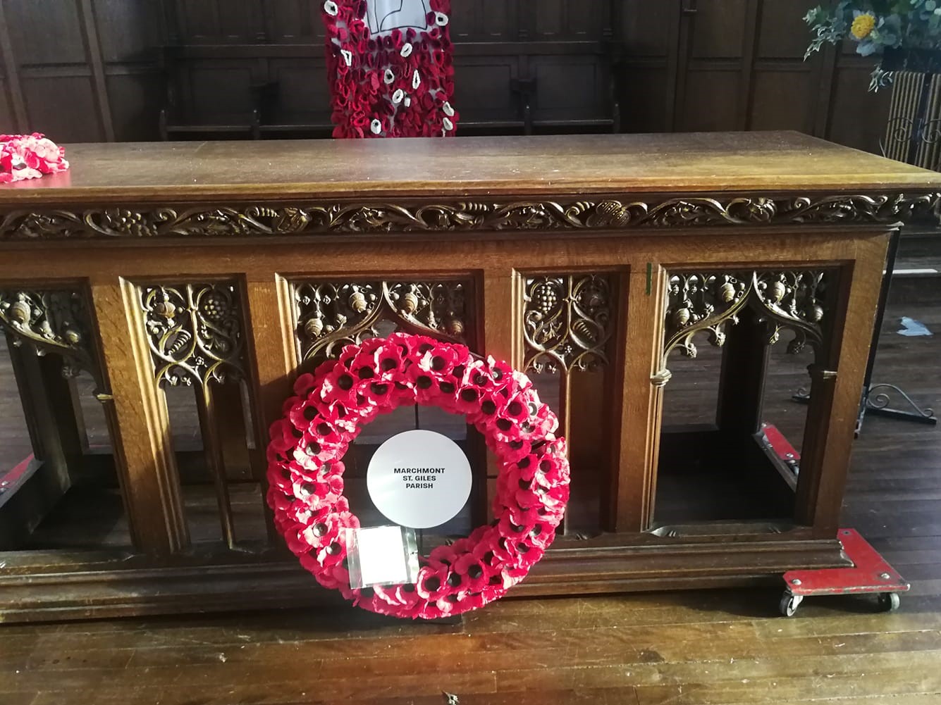 A wreath of poppies lays at the foot of an altar.