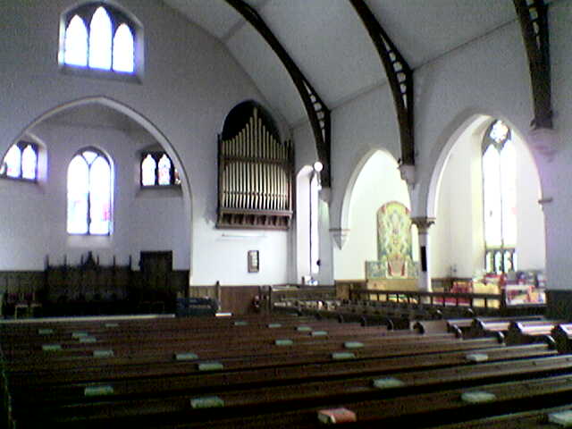 A large, white church hall with wooden pews.