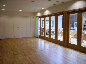 A bright room with windows along one wall and a removable partition wall.