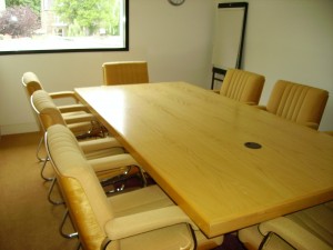 A small, carpeted conference room with comfy yellow chairs.