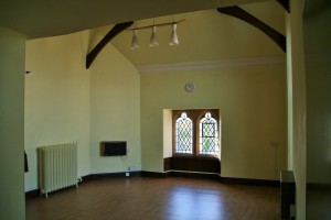 A room with high ceilings, a hard floor and stained glass windows.